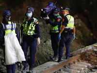 Police officers remove belongings from and conduct investigations at a scene where a train carrying 490 people has been derailed, in Hualien...