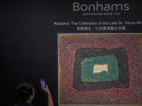 A Man Takes a photo with his cellphone of an oil on canvas painting Titled 'Untitled' by Artist Yayoi Kusama painted on 1965, estamited to a...