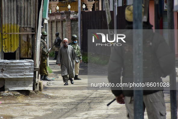 A Kashmiri man walk besides the Indian forces in a residential area where the militants were believed to be trapped during cordon in Gulab B...