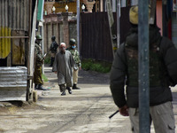 A Kashmiri man walk besides the Indian forces in a residential area where the militants were believed to be trapped during cordon in Gulab B...