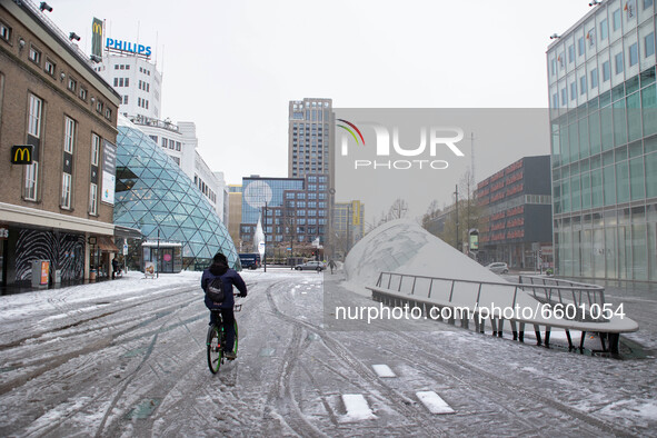 Melting snow in Eindhoven city center in 18 Septemberplein square with a man cycling a bike. The third day of the unusual April snowfall in...