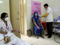 A woman reacts as she receives a dose of COVISHIELD coronavirus disease (COVID-19) vaccine manufactured by Serum Institute of India, at a go...