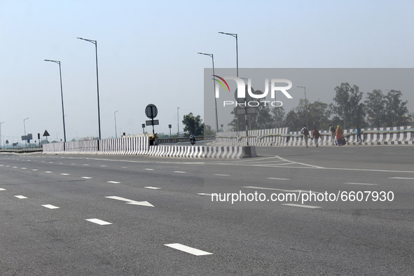 Stranded passengers walk on a blocked road at KMP Expressway (Kundli-Manesar-Palwal) during a 24-hour blockade by farmers as a part of their...