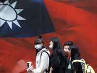 Taiwanese people wearing a face walk mask pass a Taiwan flag banner, amid heated tensions with Beijing, in Taipei, Taiwan, 11 April 2021. Wi...