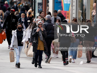 Shoppers carry bags along Oxford Street in London, England, on April 12, 2021. Coronavirus lockdown measures were further eased across Engla...