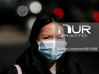 A woman wearing a face mask waits at a bus stop on Oxford Street in London, England, on April 12, 2021. Coronavirus lockdown measures were f...
