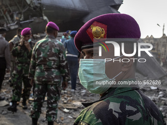 An Indonesian military covered his face standing on debris of air force-owned aircraft that crashed in Medan, North Sumatra, Indonesia on Ju...