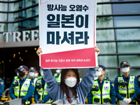 A protester holds a banner say the Japanese Government Should Drink Fukushima Radioactive Contaminated Water during a protest against the Ja...