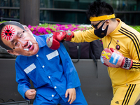 A protester punches his fellow protester who wearing a mask of Japanese Prime Minister Yoshihide Suga during a protest against the Japanese...