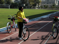  A Palestinian woman rides bicycle at the Yarmouk Stadium in Gaza city on April 28, 2021. The 