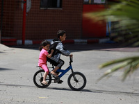 Palestinian children ride a bicycle in Gaza city on April 28, 2021. (
