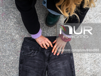 A woman places jeans on the floor during a flashmob to protest against gender violence in Piazza Castello on April 28, 2021 in Piazza Castel...