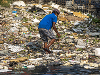 A man were seen finds plastic wastage in the Buriganga River in Dhaka on April 29, 2021. The water looks black as the city garbage are throw...