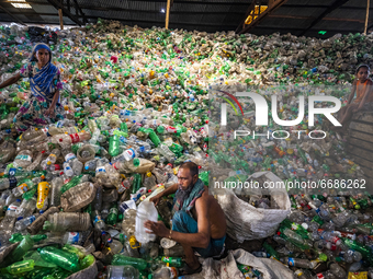 Woman labourers sort through polyethylene terephthalate (PET) bottles in a recycling factory in Dhaka, Bangladesh, on May 5, 2021. Recycling...