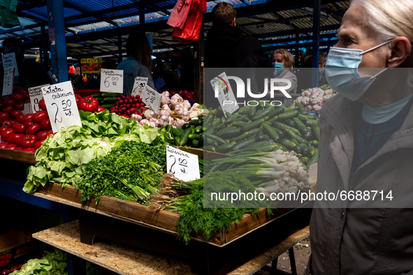A woman in protective face mask browse through fresh spring green vegetable at outdoor market in central Krakow, Poland on May 6, 2021. 