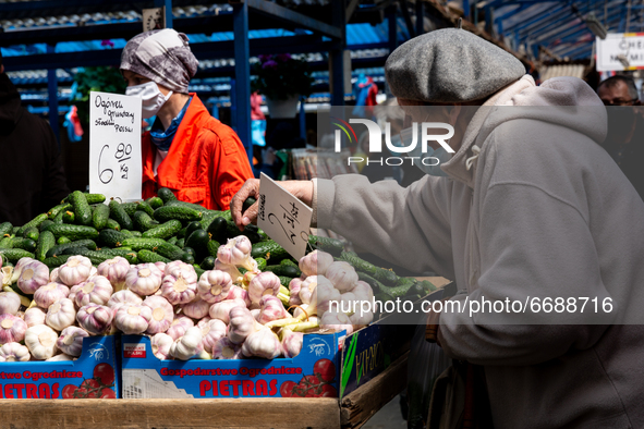 A woman in protective face mask browse through fresh spring green vegetable at outdoor market in central Krakow, Poland on May 6, 2021. 