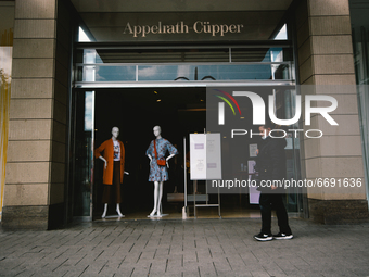 A woman with face mask walks in front of Appelrath Cuepper retailer store in city center of Cologne, Germany on May 7, 2021 (