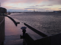 Woman with umbrella walk along the embankment of the Neva River. Storm clouds hang over the Peter and Paul Fortress in St. Petersburg, Russi...