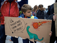 A young boy holds a placard depicting a dinosaur and reading 'We also thought we had time'. For the 2nd time, citizens, NGOs, associations t...