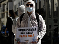Members of the Animal Save group, wearing protective suits and carrying banners, hold a rally to raise awareness about the relationship betw...