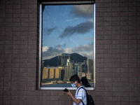 A Man wearing a face mask walks pass a Reflection of the Hong Kong City Skyline on a window in Hong Kong, Monday, May 10, 2021. (