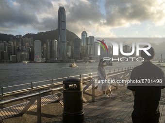 A Women pose for a photo in front the Hong Kong City Skyline in Hong Kong, Monday, May 10, 2021. (