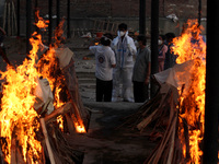 Family members perform the cremation of a person, who died due to the coronavirus disease (COVID-19), at a crematorium in New Delhi, India o...