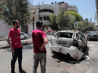 People inspect a car that was hit in an Israeli airstrike that killed three people in the car, on the main road in Gaza City, Wednesday, May...