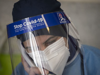 An Iranian medical personnel wearing a protective face mask and a face shield speaks on a phone before vaccinating a woman by the China's Si...