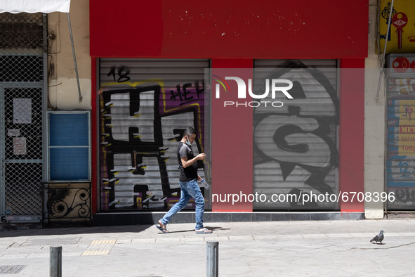A man seen walking past a closed store at the center of Athens, Greece on May 15, 2021. 