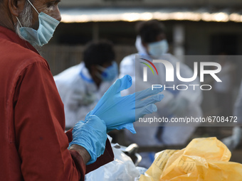 A worker wearing gloves  to bury a body of a person who died of COVID-19 coronavirus, in Guwahati, Assam, India on 7 May 2021. A new wave of...