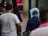 A person walks in the downtown covered with a plastic bag on his head   to avoid getting wet from the rains , due the city has dawned with h...