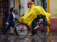 A person rides on bicycle covered with a raincoat , due the city has dawned with heavy rains and more rains are forecast according to the na...