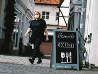 opening cafe sign is seen as a waitress walks by in Soest, Germany on May 12, 2021 as Soest and Lippstadt are two the first model cities to...