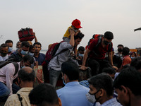 People rush with their belongings to board a ferry at Mawa Ferry Terminal to get home to celebrate Eid al-Fitr, after the government imposed...