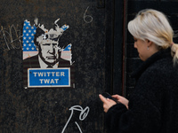 A woman walks past a poster with an image of former US President Donald Trump and the words 'Twitter Twat' seen in Dublin city center.
On We...