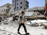 A Palestinian boy walks in front of Al-Walid building which was destroyed in an Israeli airstrike on Gaza city, on May 13, 2021.  (