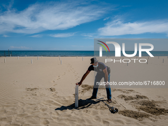 A worker places the poles for the umbrellas on the beach of Margherita di Savoia, Italy  on May 14, 2021.
The managers of bathing beaches h...