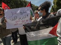 A protester lifts a placard that reads in Arabic, normalization with the state of Israel kills more than the coronavirus, Criminalize the no...