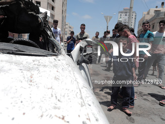 Palestinians inspect a civilian car that has been bombed by an Israeli bomb near the Gaza Sea, Gaza City, May 17, 2021(