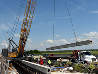 A crane lifts a pile for a bridge over the St. Johns River during the construction of the $2.7 billion, 170-mile Brightline high-speed rail...