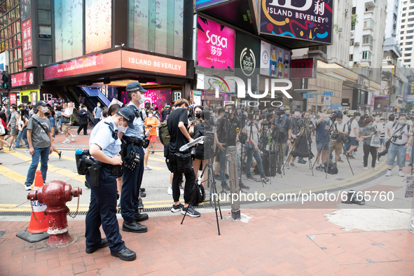 Police monitor an activist talking to livestreamers in Causeway Bay, in Hong Kong, China, on May 30, 2021. 