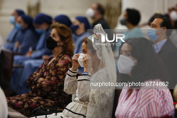 A woman wearing a traditional back comb (peineta) puts a face mask on during the traditional Mass of the Corpus Christi in the Cathedral on...