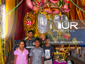 Hindu devotees pose by a large clay idol of Lord Ganesha (Lord Ganesh) at a pandal (temporary shrine) along the roadside during the festival...