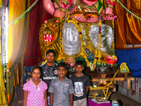 Hindu devotees pose by a large clay idol of Lord Ganesha (Lord Ganesh) at a pandal (temporary shrine) along the roadside during the festival...