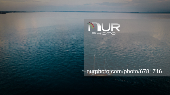 A drone view of a boat on the Lake Garda, in Garda, Italy, on June 5, 2021, during the sunset.  Lake Garda is the largest lake in Italy and...