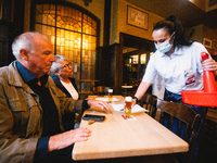 a staff carries the beer to the table inside of Peters Brauhaus in Cologne, Germany on June 6, 2021 as cologne allows indoor dinning with co...