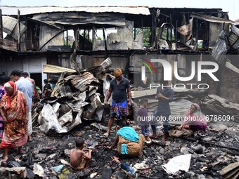 Slum-dwellers search for their belongings after a fire swept through the slum on June 07, 2021 in Dhaka, Bangladesh.  (