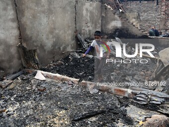 A kid is seen walking in a burned house after a fire swept through the slum on June 07, 2021 in Dhaka, Bangladesh.  (