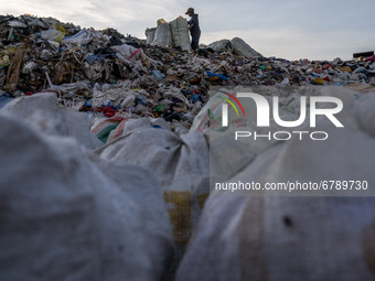 A scavenger puts his scavenged goods into a sack at the Poi Panda landfill, Kawatuna, Palu City, Central Sulawesi Province, Indonesia on Jun...